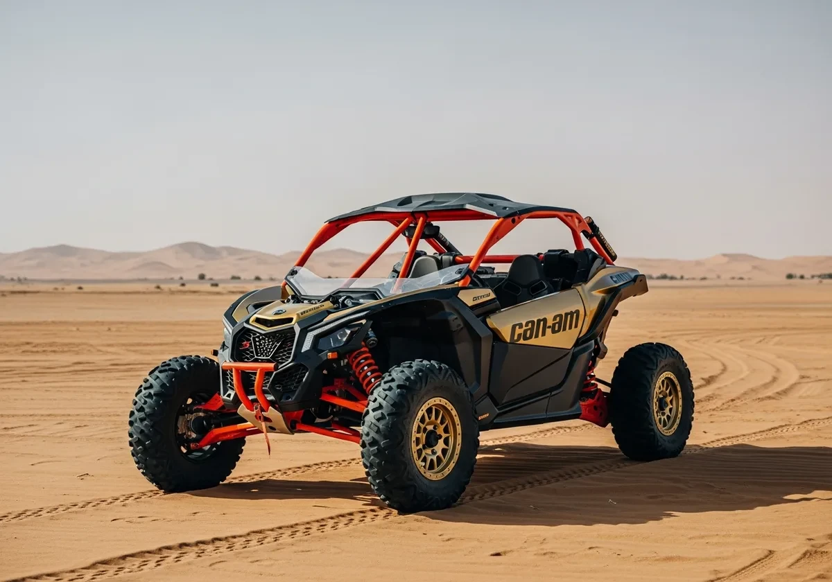 Gold and black Can-Am Maverick X3 buggy parked on open desert sand